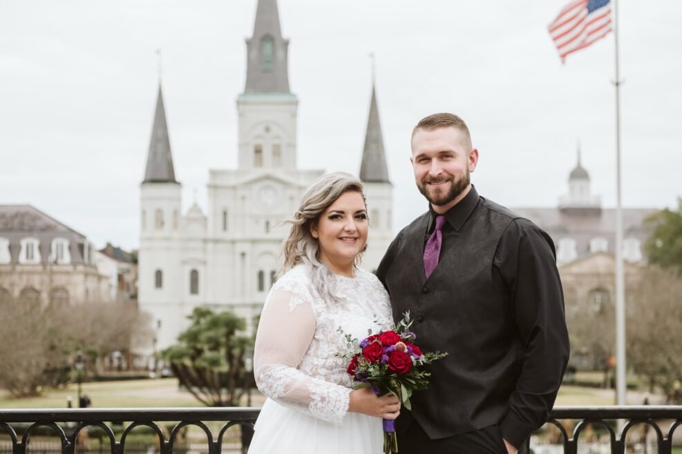 A bride and groom pose for a photo in front of the St. Louis Cathedral located in the French quarter of New Orleans after eloping.
