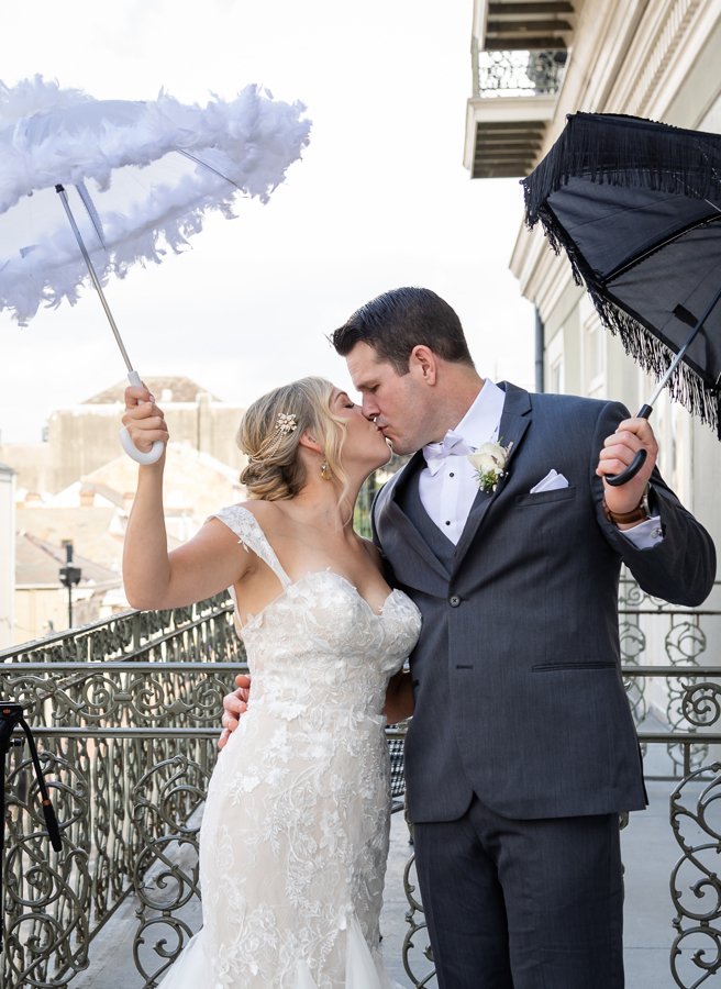 Bride and groom kissing under umbrella outside Bourbon Orleans Hotel during romantic New Orleans elopement
