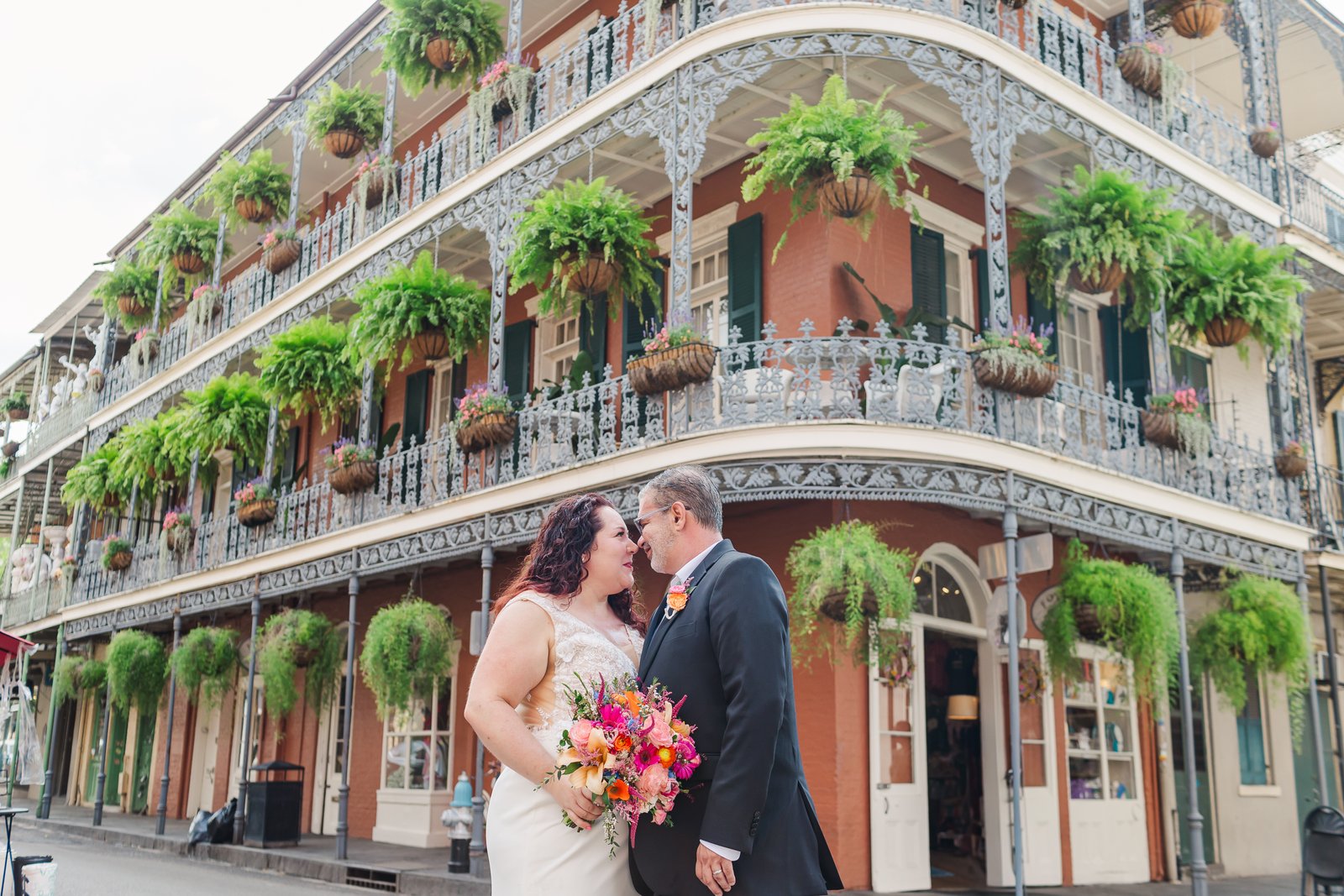 A couple holding hands in front of a colorful wall in New Orleans.