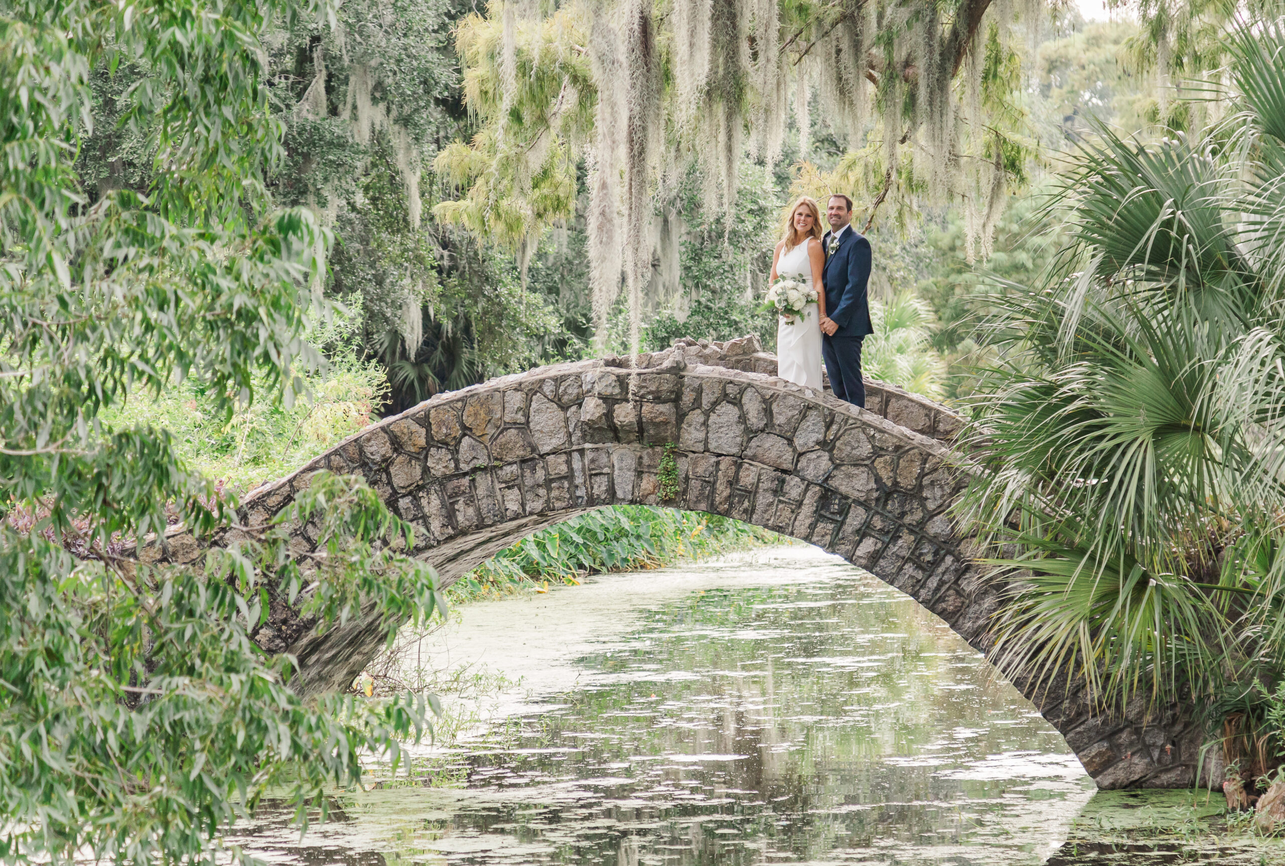 couple posing for their elopement on the cobblestone bridge in city park