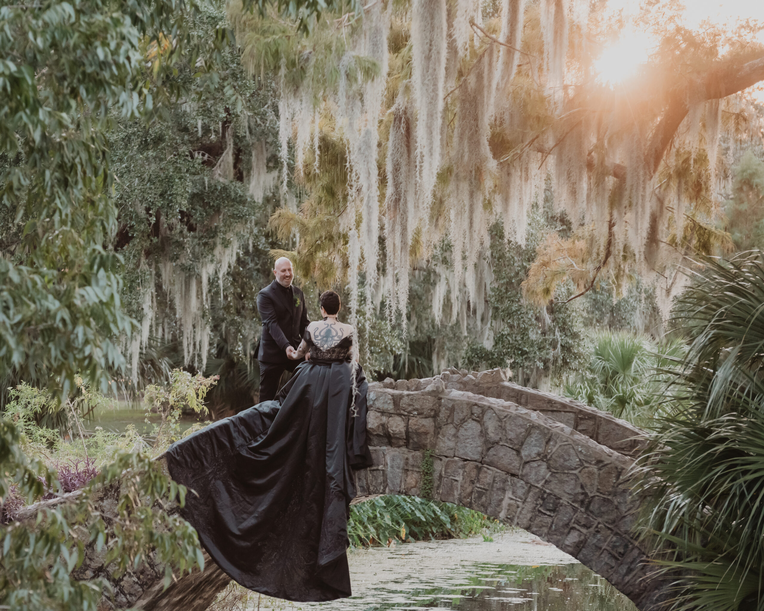 couple just married on the cobblestone bridge in New Orleans with sweeping black dress