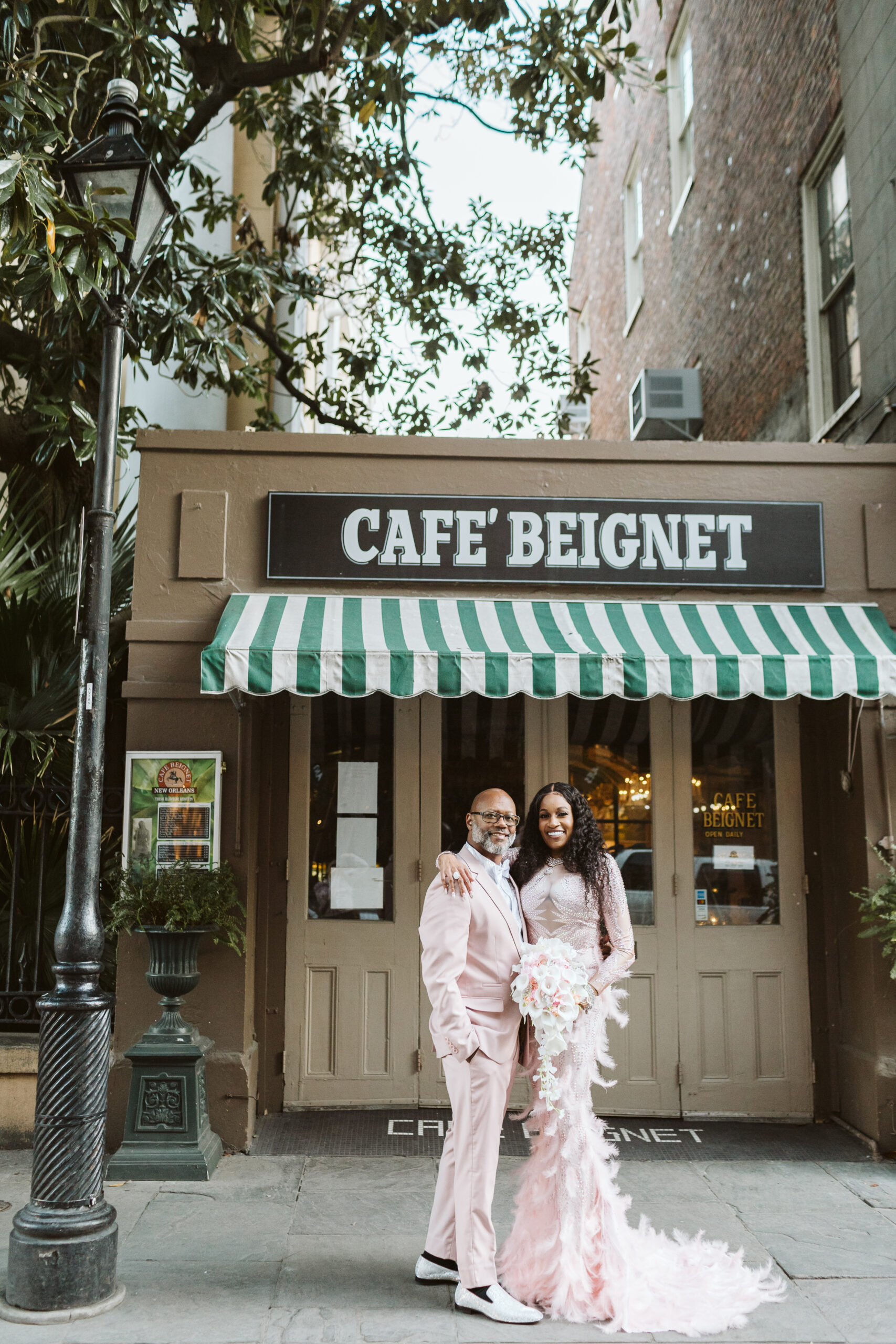 couple posing after their French quarter wedding in front of cafe beignet