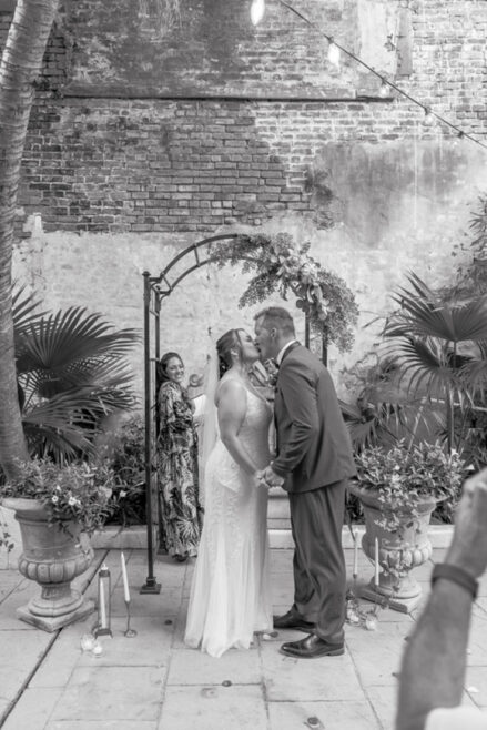 Bride and groom sharing their first kiss in an outdoor courtyard in New Orleans.