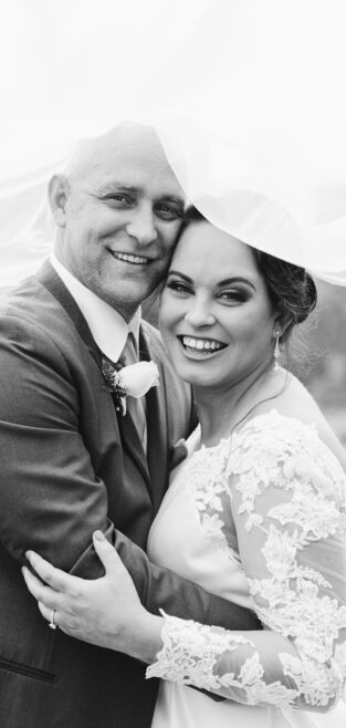 Bride and groom smiling under a veil during their intimate New Orleans elopement.