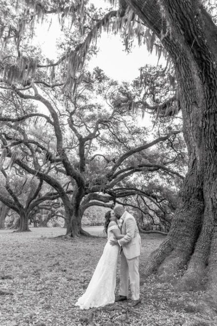 Bride and groom sharing a kiss under sprawling oak trees during their New Orleans elopement.