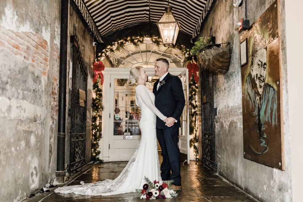 Eloped couple posing in the arched entrance of The Court of Two Sisters in New Orleans’ French Quarter.