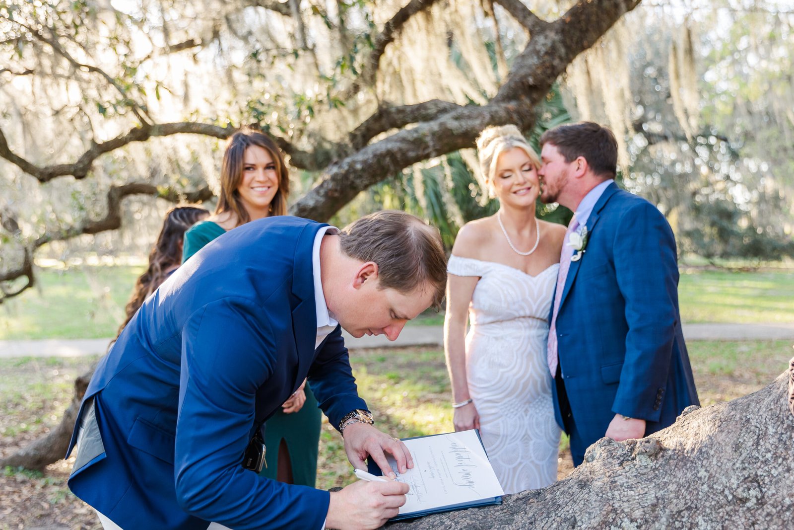 Couple standing beneath large oak trees after eloping in City Park, New Orleans