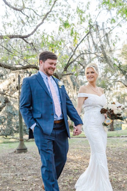 Newly married couple walking through the trees in City Park