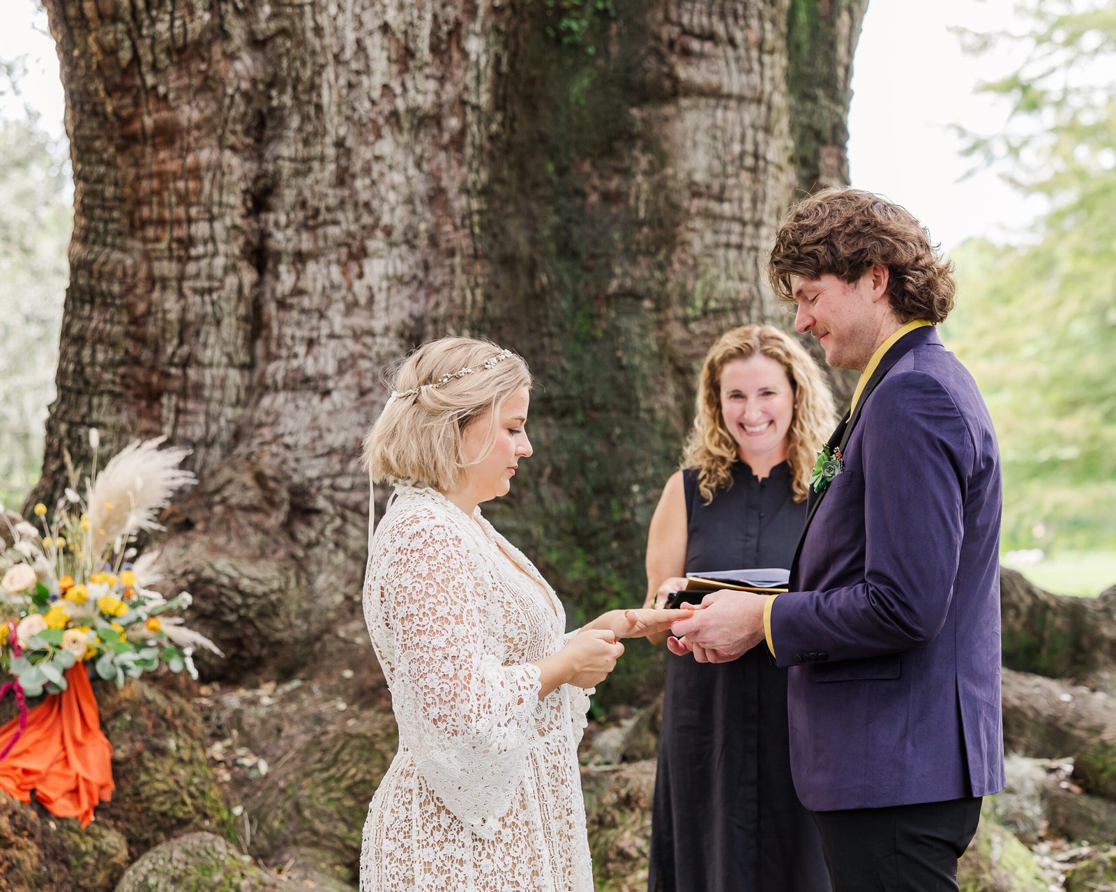 couple stands under sprawling oak branches to exchange rings