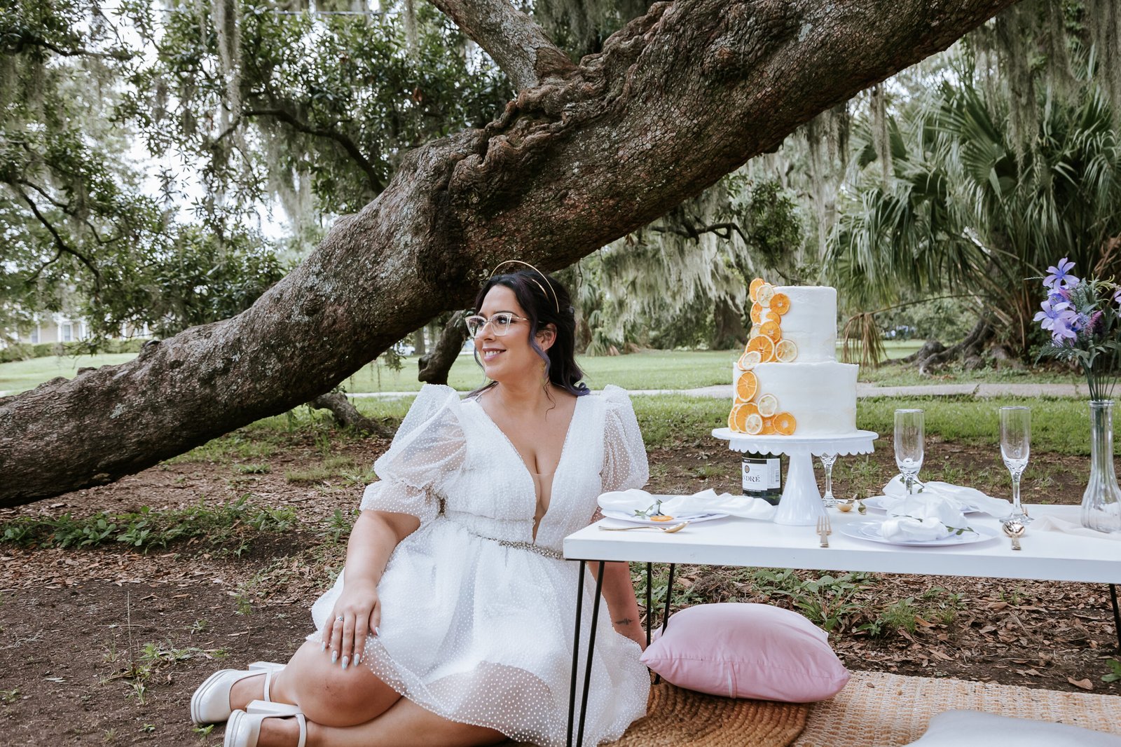 Elopement photo of bride with her cake under moss-covered trees in the background during her new Orleans elopement