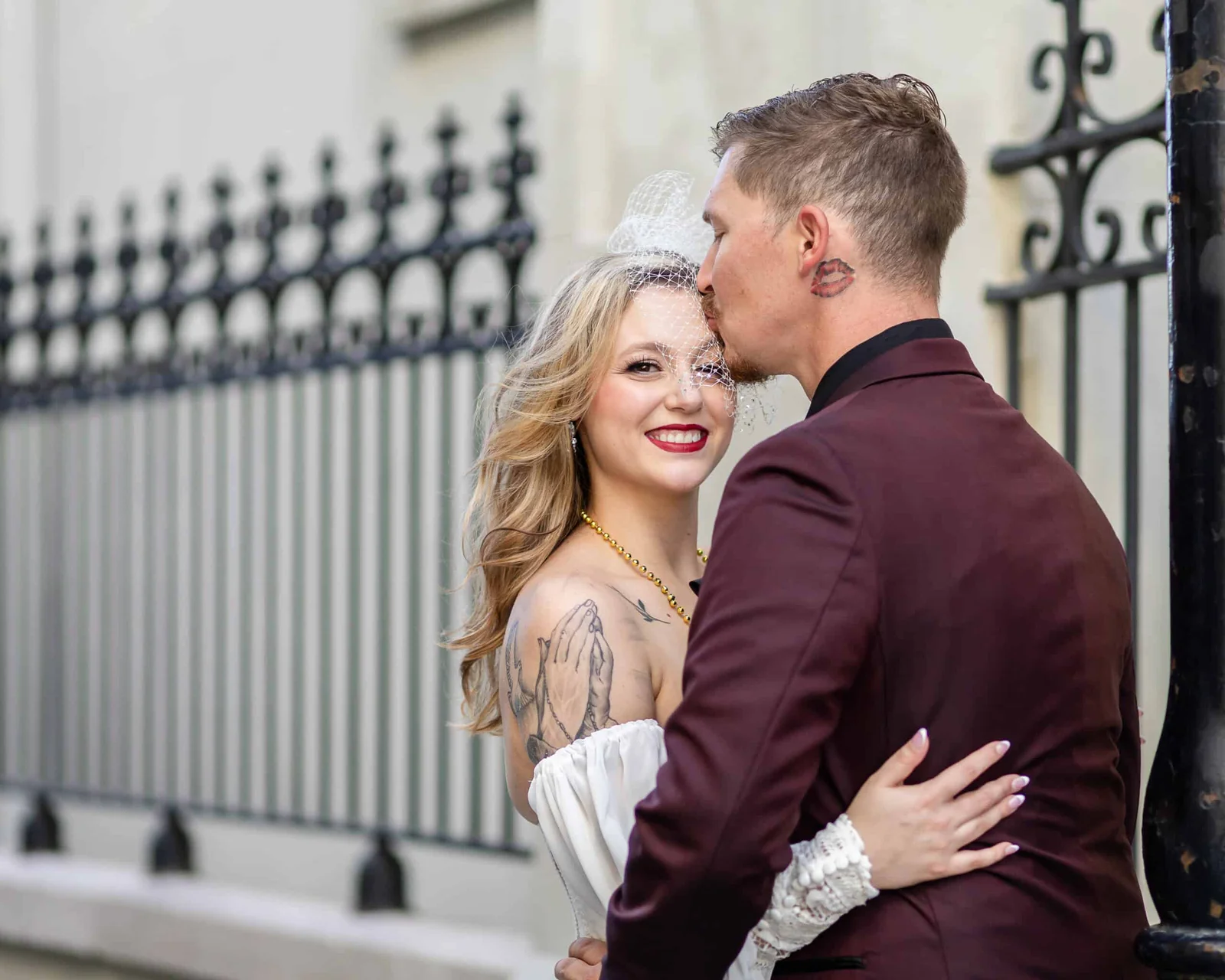 Bride and groom embrace during their New Orleans elopement, with the groom kissing the bride's forehead.
