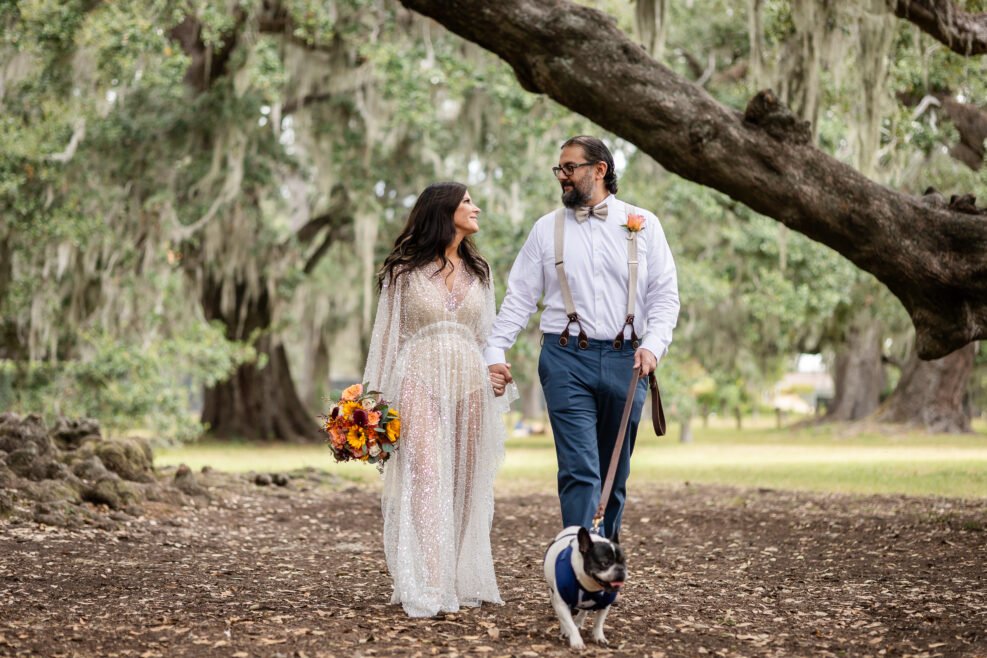 Bride and groom walking with their dog beneath the Tree of Life in New Orleans
