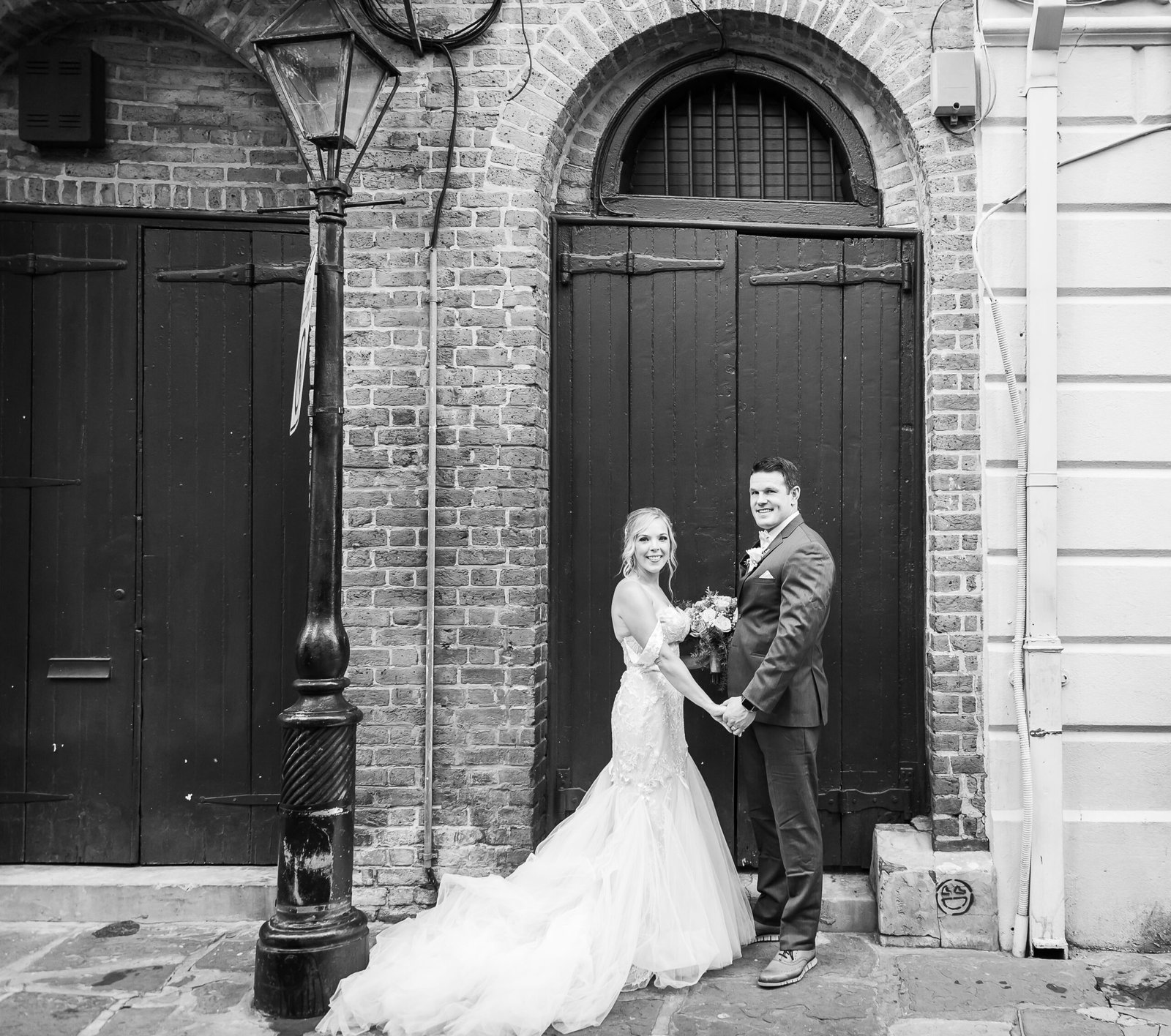 Black and white photo of a couple holding hands, walking through the French Quarter after eloping in New Orleans.