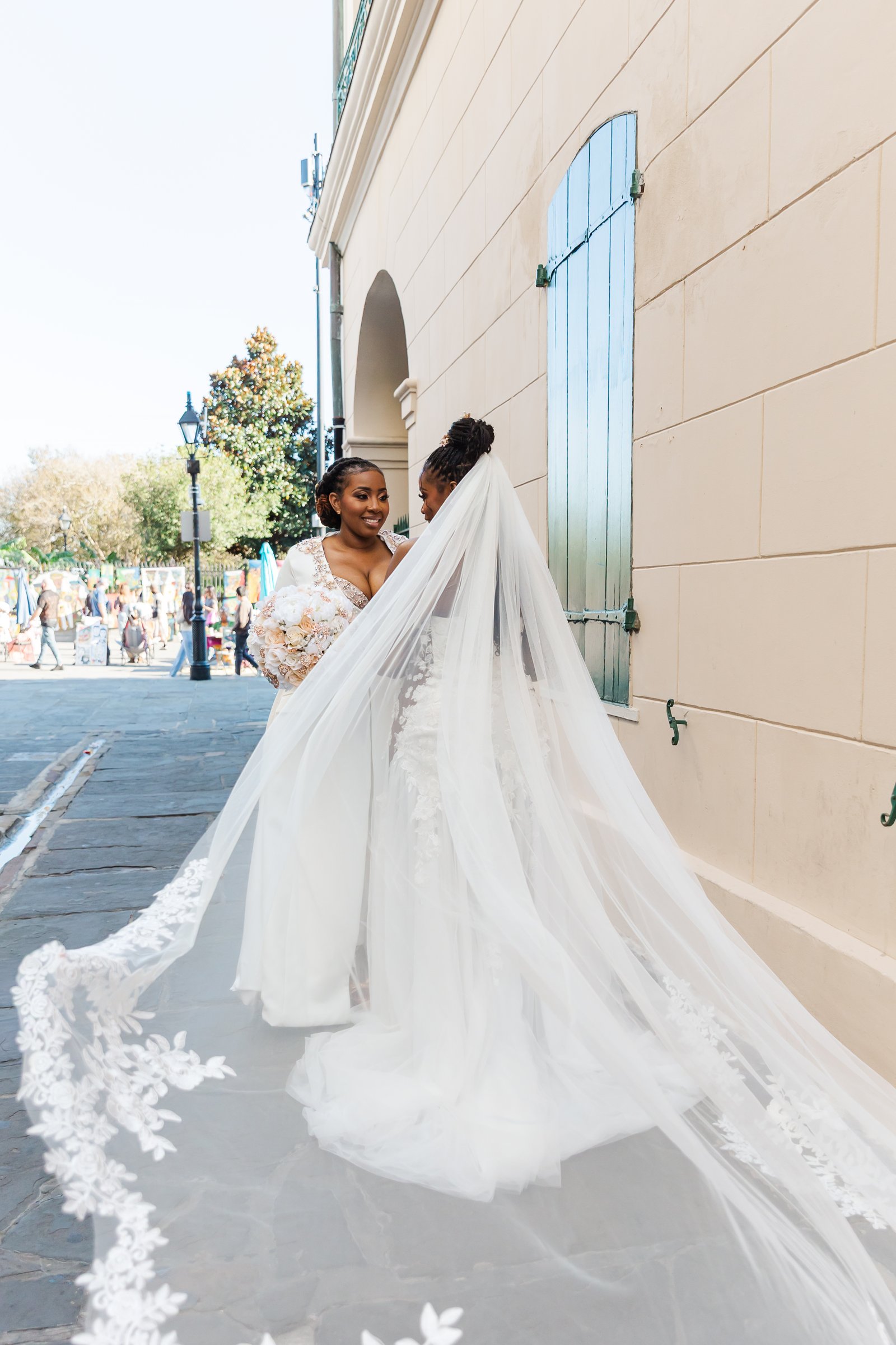 Two brides posing for their wedding photos in Pirates Alley New Orleans before their elopement
